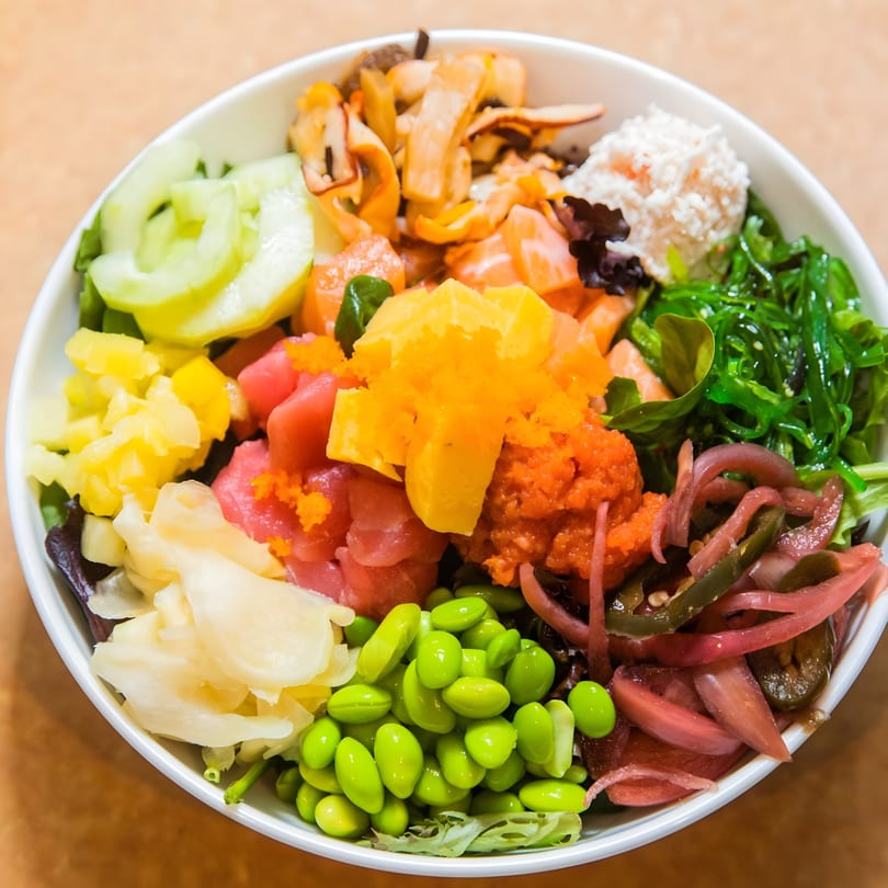 A colorful poke bowl from Jimmy's Poke & Sushi Burrito, filled with fresh fish, edamame, and various toppings.